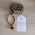 Coffret cadeau FIROUZ ART avec collier en œil de taureau, coffret Khatam artisanal et carte personnalisée.