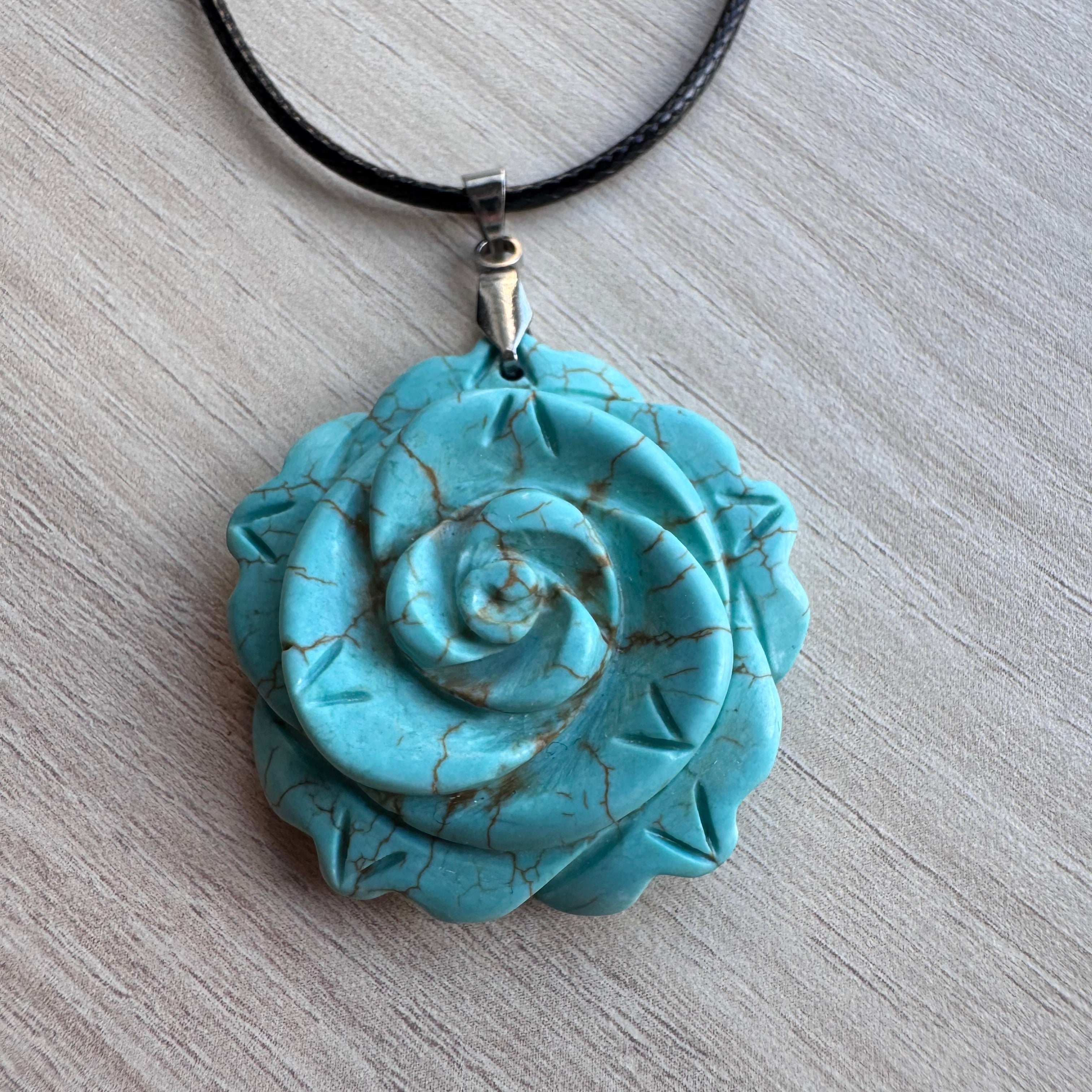 Gros plan d’un pendentif en forme de rose sculptée dans une pierre bleu turquoise veinée